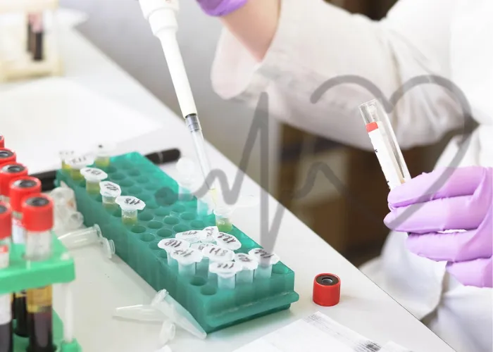 Technician handling blood sample test tubes in a laboratory.