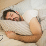 A young man peacefully sleeping in bed with striped pillows