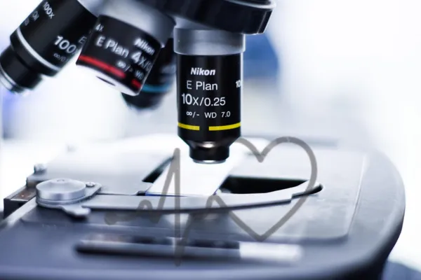 Detailed image showing the objective lenses of a microscope focusing on a glass slide and representing scientific examination and biopsy sample analysis.